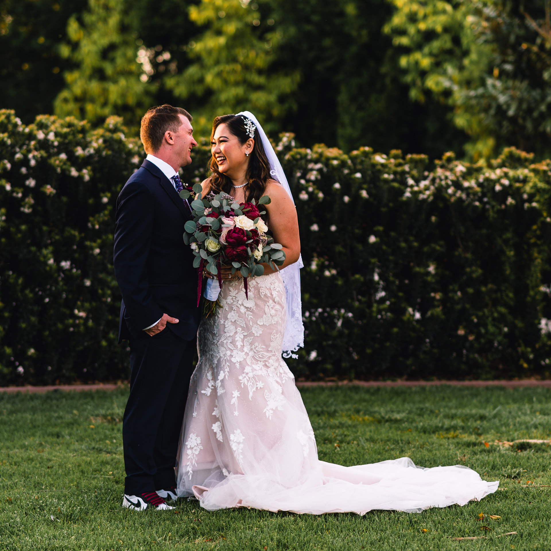 Bride and groom smiling at each other in garden